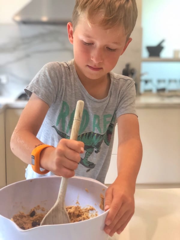kid mixing ingredients using kitchen spoon in a bowl