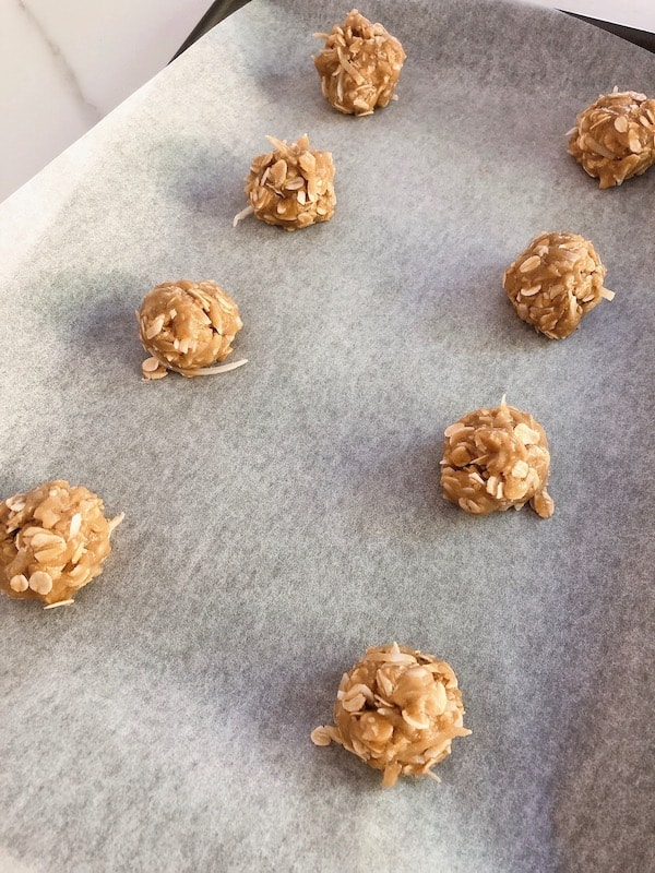 Scoops of Anzac biscuit cookie dough on baking tray. 