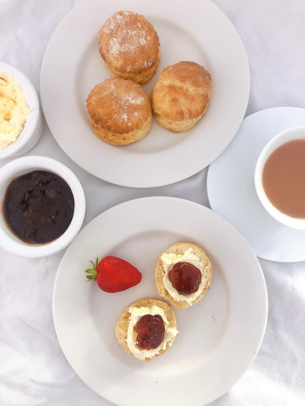 A plate of scones with strawberry and jam shoot on top
