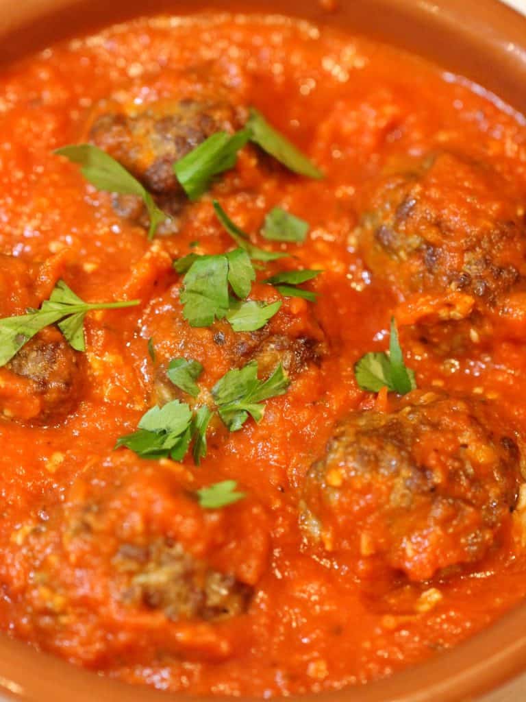 Italian Baked Meatballs in tomato sauce with parsley close-up