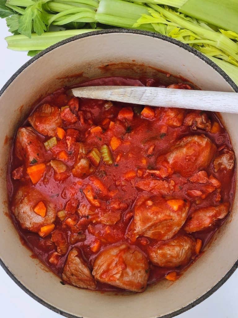 A bowl of lamb ragu with wooden spoon