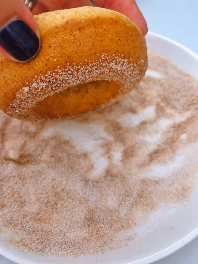 dipping donut on the sugar/cinnamon mixture