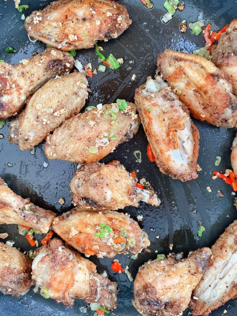 Tossing wings in garlic, spring onions and chilli