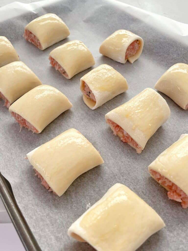 rolled pastry with filling and egg wash on a baking tray.