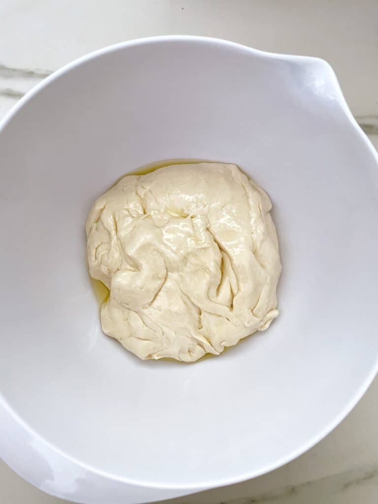 dough with oil in a greased bowl