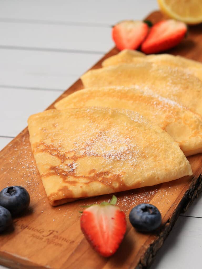 Thermomix crepes with a dusting of icing sugar and fresh berries