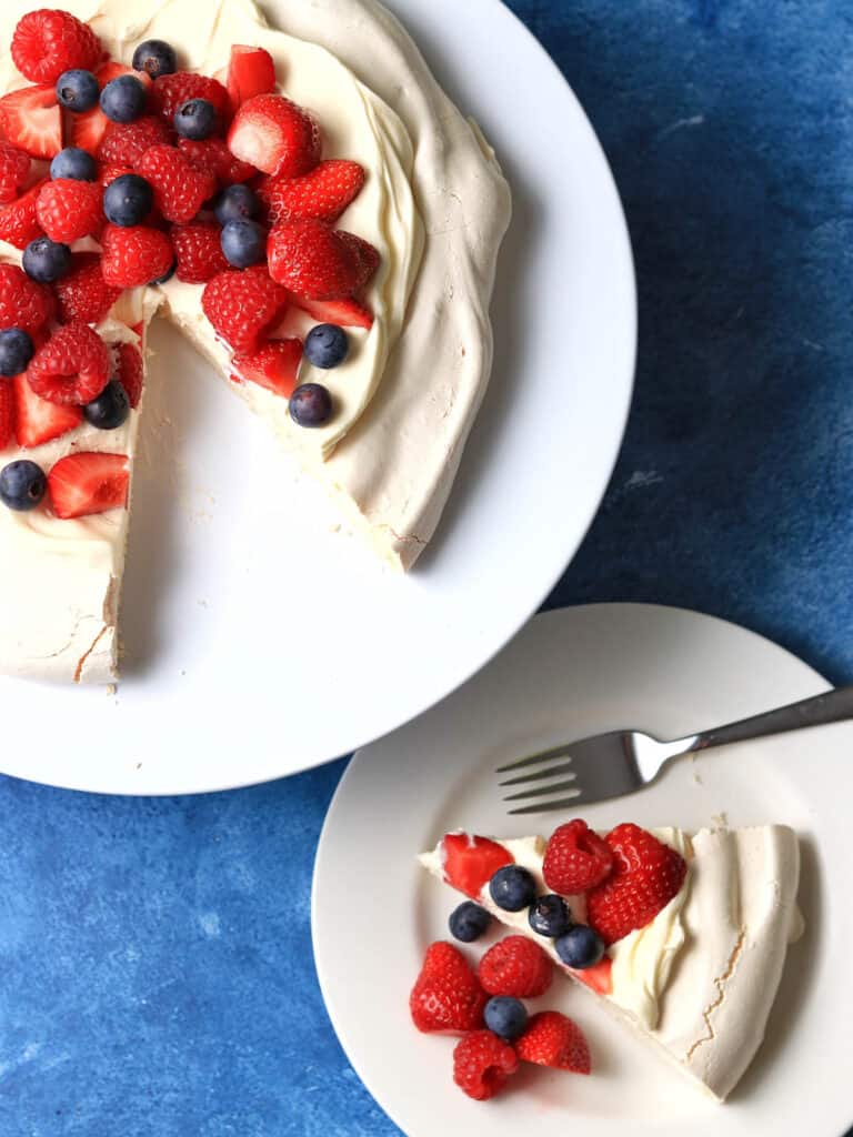 A plate of Thermomix Pavlova with one slice beside and fork.