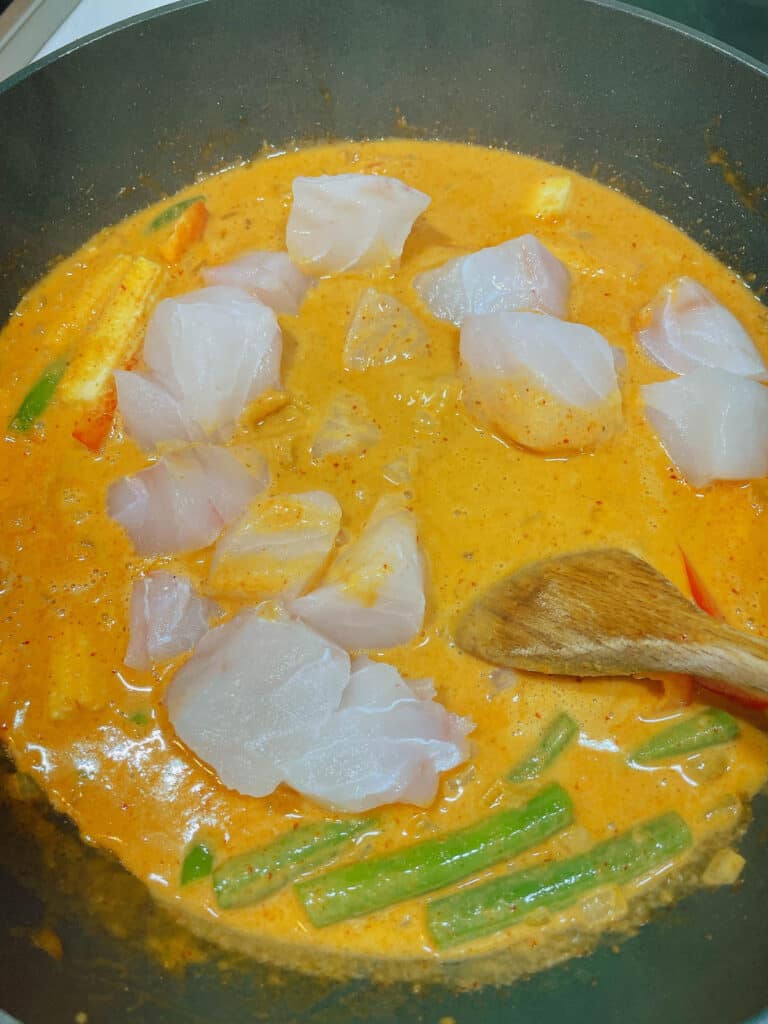 adding fish and vegetables on curry sauce