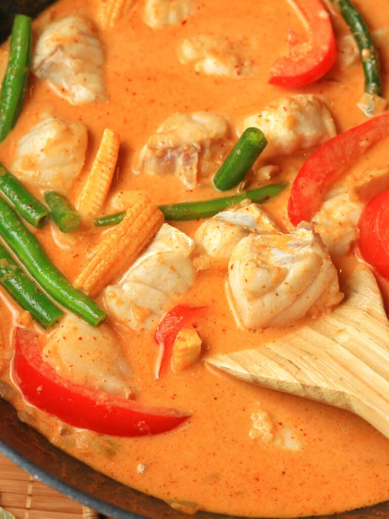 Close up of fish and vegetables in Thai red curry sauce