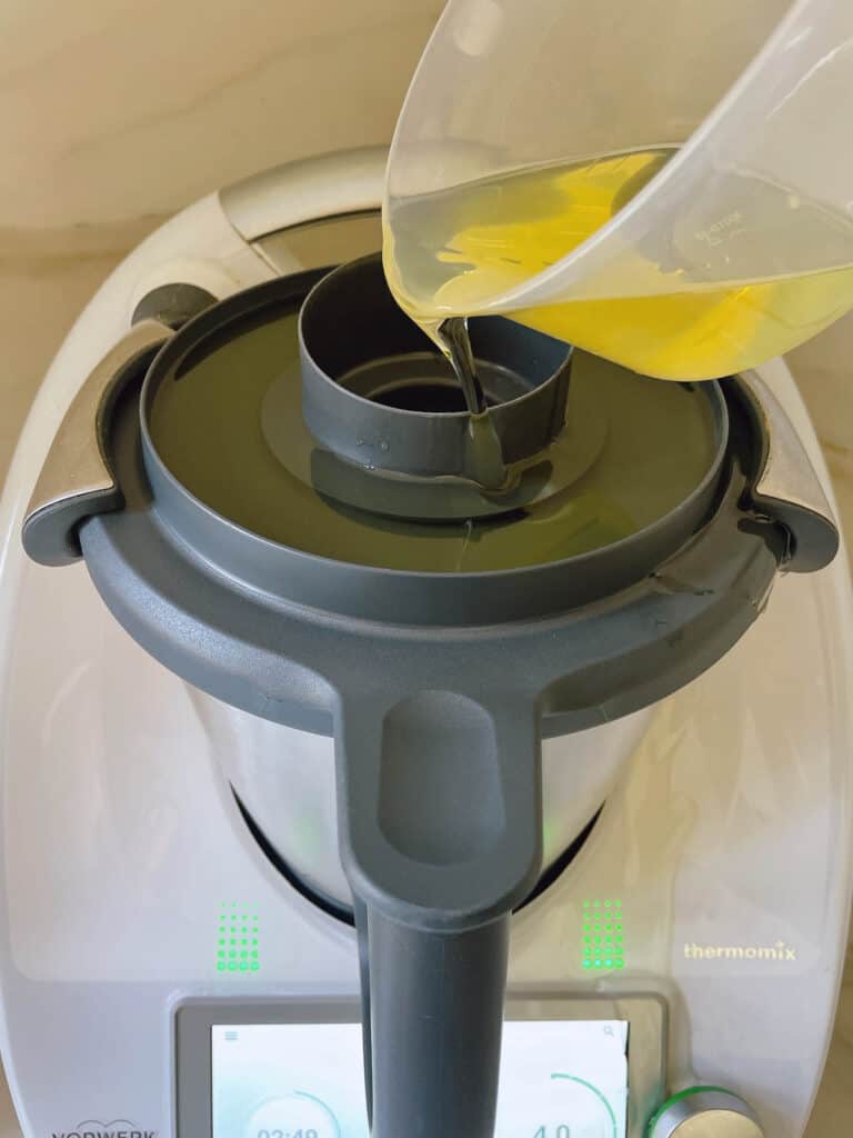 Pouring oil onto the lid of the Thermomix for making mayonnaise.