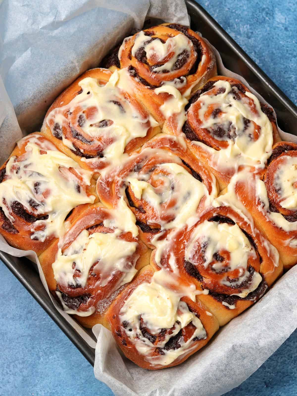 Cinnamon rolls in cake tin with cream cheese frosting. 