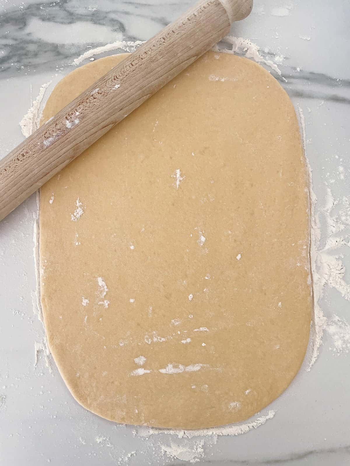 Cinnamon roll dough rolled out into a rectangle. 