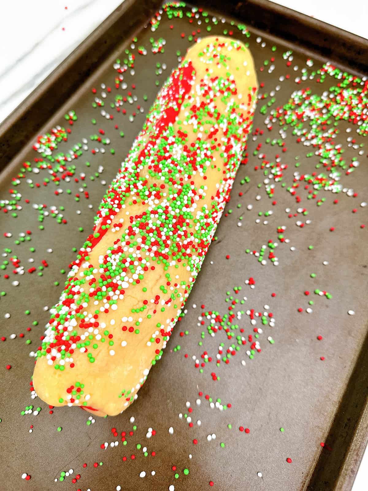 Rolling cookie dough in sprinkles.