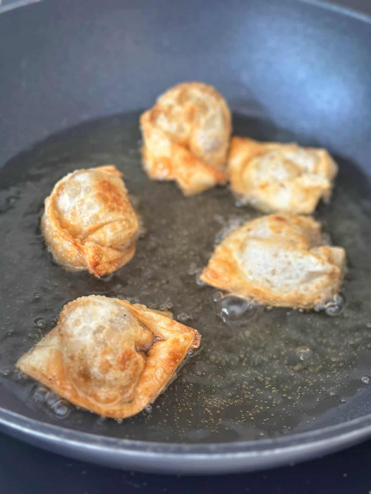 Wontons frying in oil.