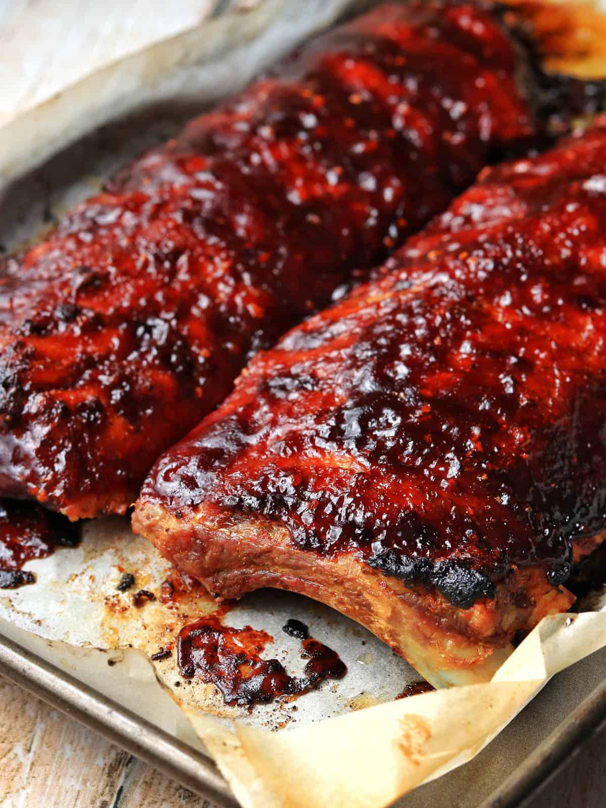 Baked barbecue ribs on a baking tray, fresh from the oven.