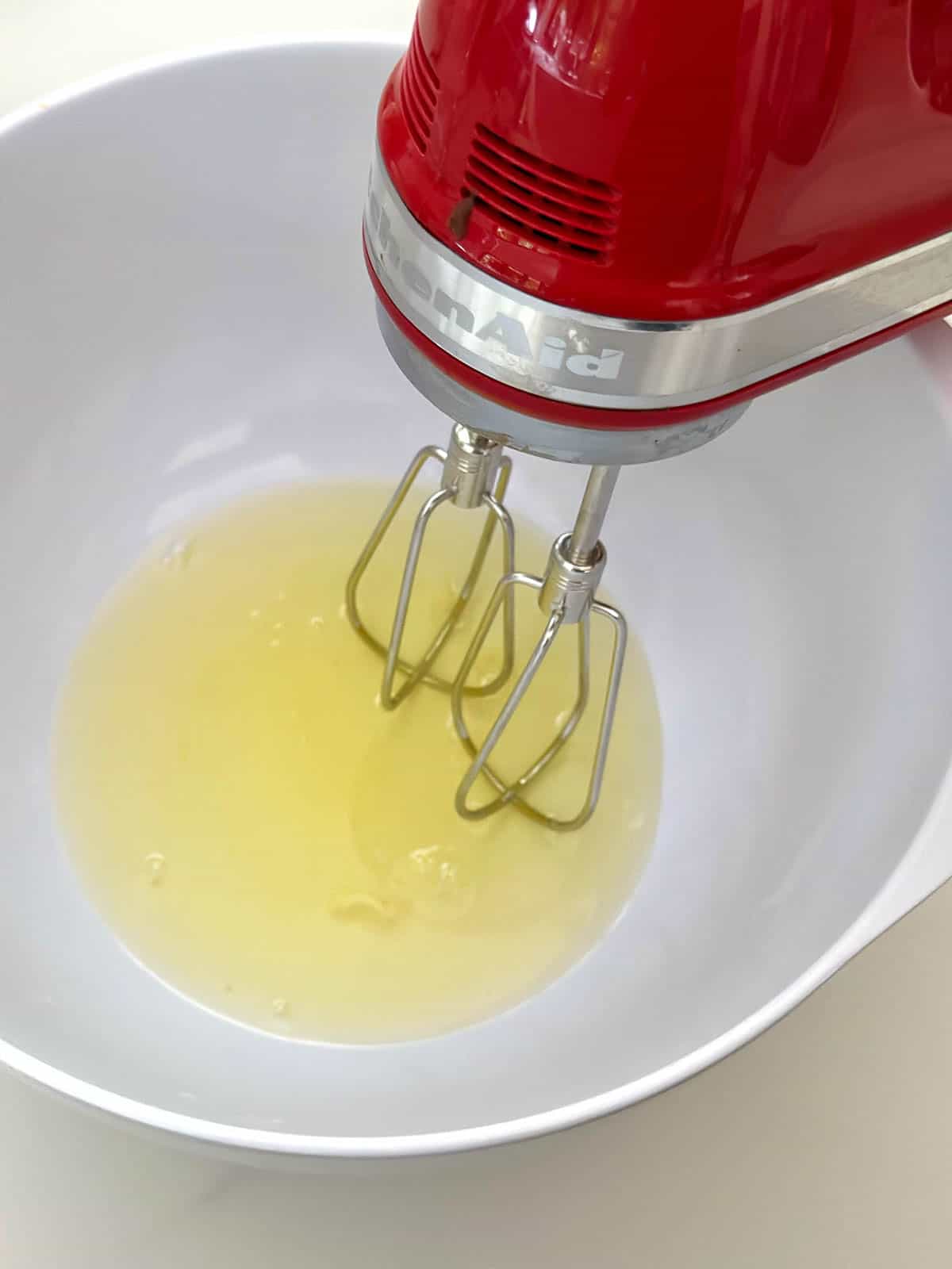 Egg whites in a bowl with an electric whisk.