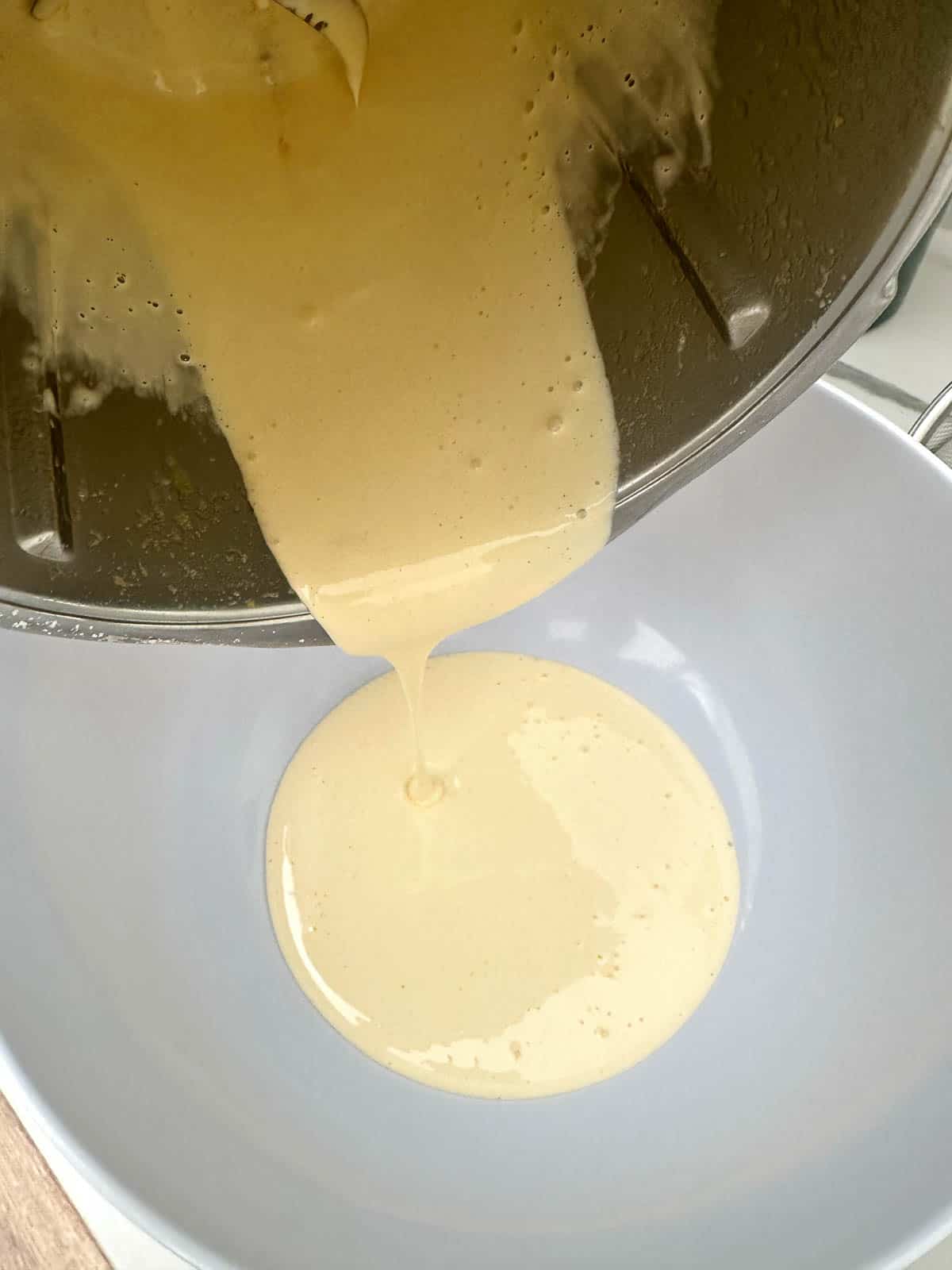 Pouring whisked egg yolks into bowl.