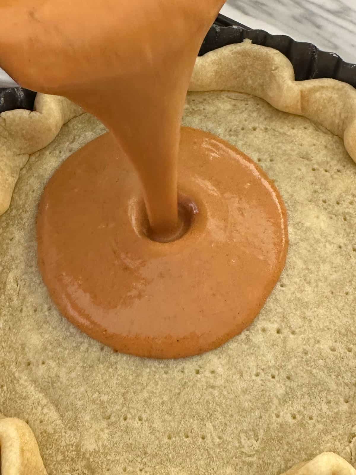 Pouring Pumpkin Pie filling into pastry case.