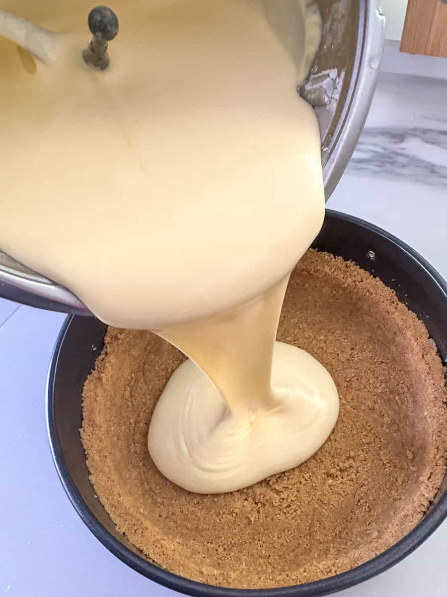 Pouring Thermomix Cheesecake filling into cake tin. 