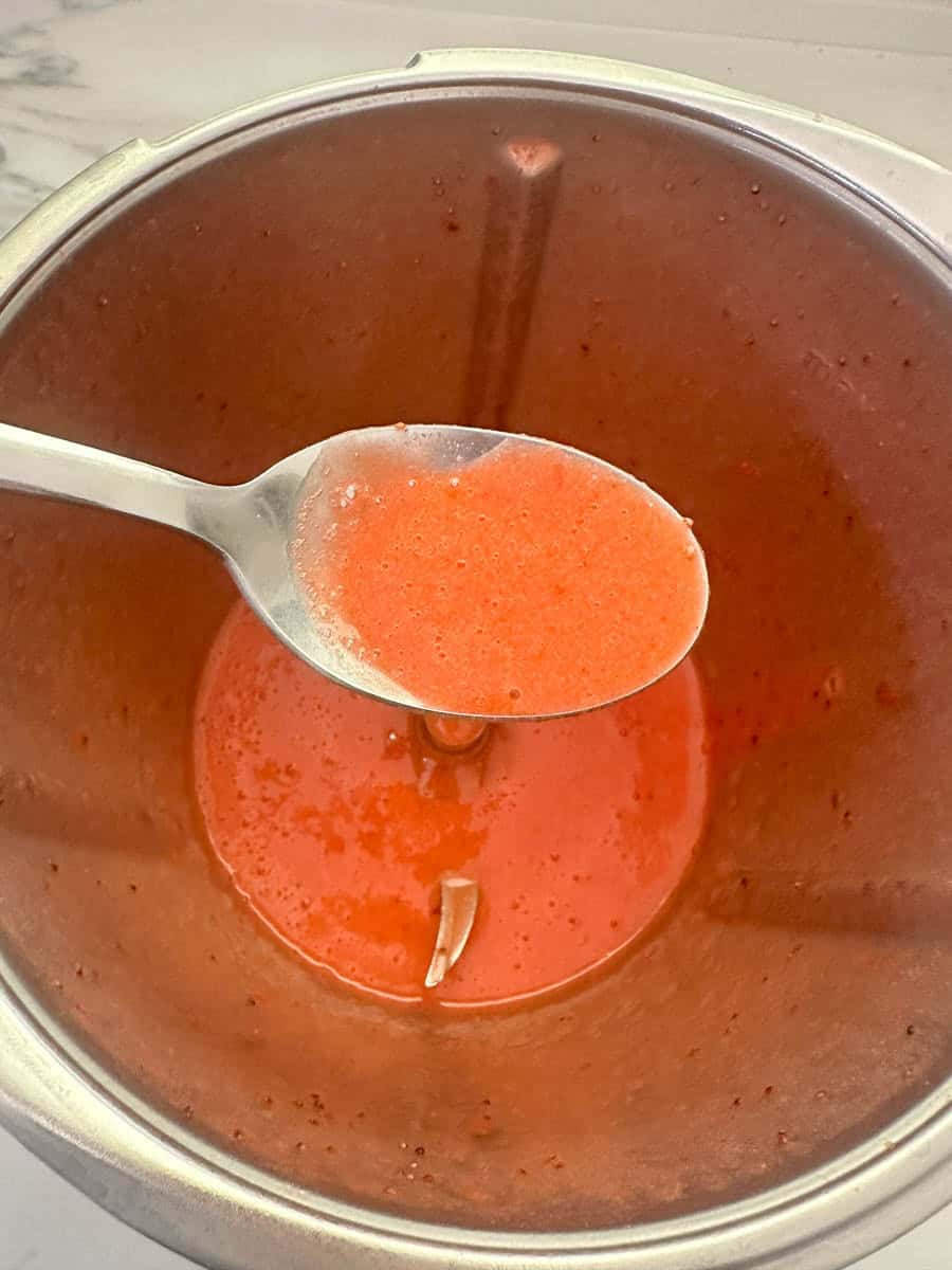 Spoon of strawberry sauce showing consistency. 
