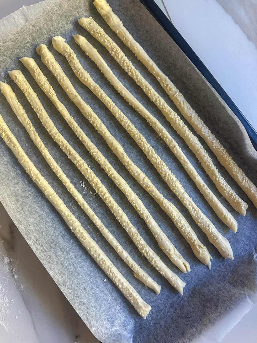 Homemade breadsticks on a baking sheet ready for the oven. 