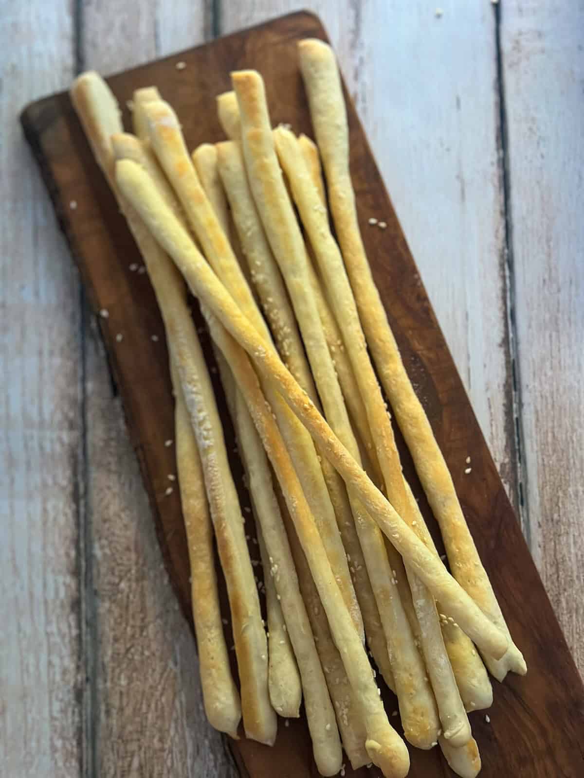 Homemade Thermomix Grissini on a bread board. 