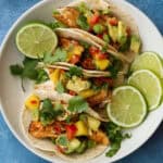 Air fryer fish tacos with mango salsa on a plate.