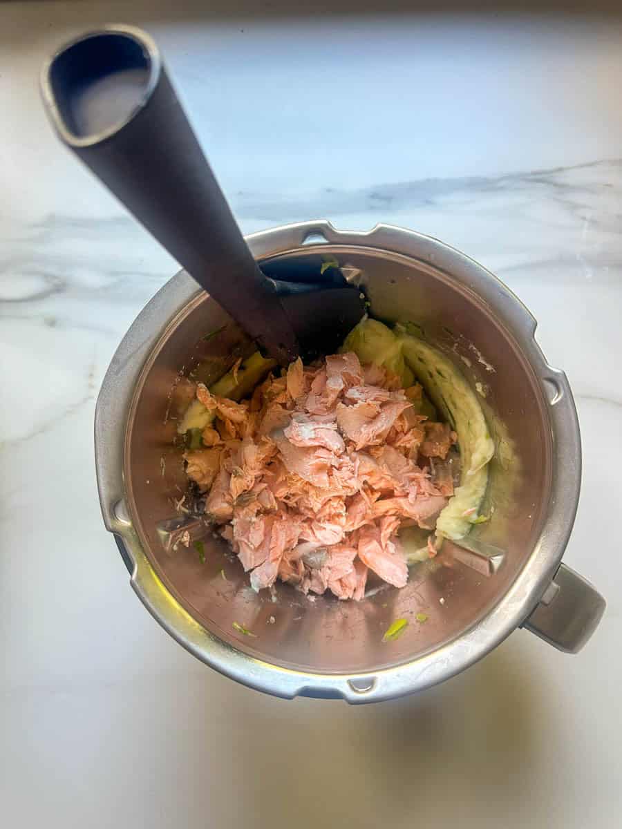 Salmon fishcake mixture in a Thermomix bowl with a spatula.