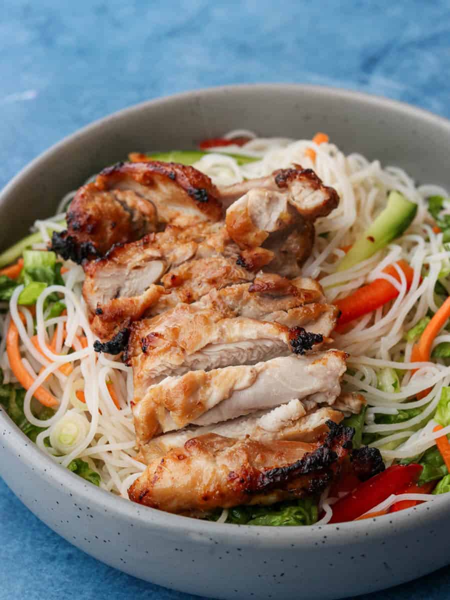 Vietnamese Noodle Salad in a bowl topped with Grilled Lemongrass Chicken.