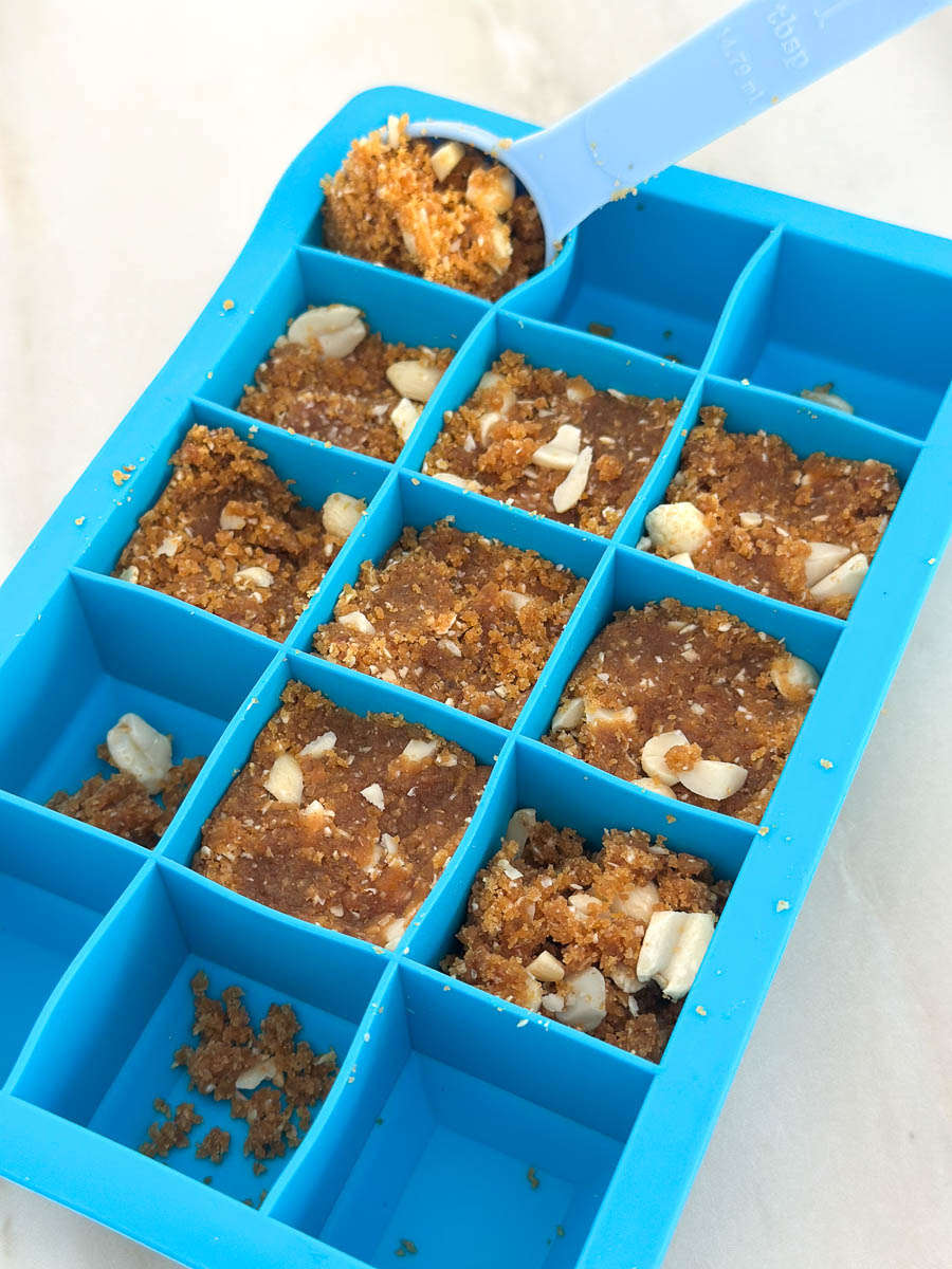 Scooping Thermomix Peanut Butter Chocolate Energy Bites mixture into an ice tray.